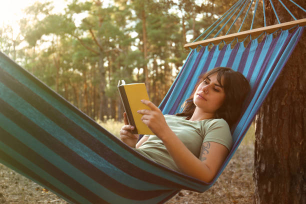 istock Woman with book resting in comfortable hammock outdoors 1365323010