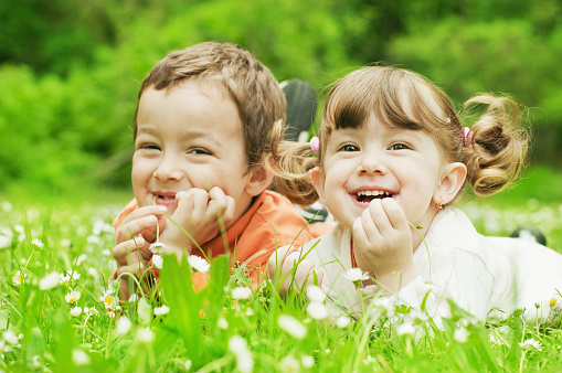 Two cute children resting on the grass in the park