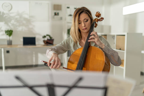 istock Female cellist sitting in studio and playing cello 1365327669