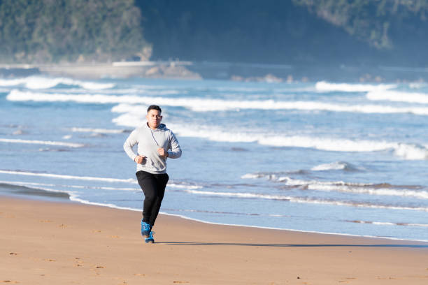 Latin sportsman running on the sand at seaside