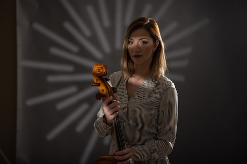 Portrait of woman while standing in studio and holding cello