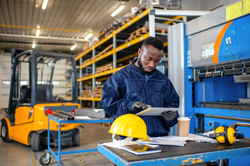 Black male engineer working on digital tablet in factory