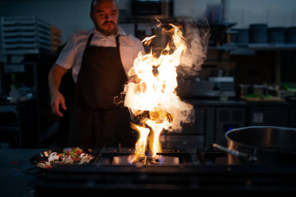 istock Professional chef preparing meal, flambing indoors in restaurant kitchen. 1365329937