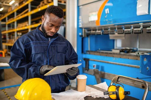 Black male engineer working on digital tablet in factory stock photo