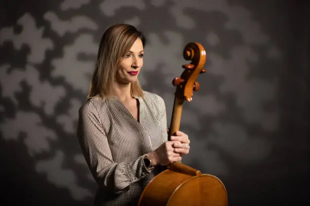 Portrait of woman while standing in studio and holding cello