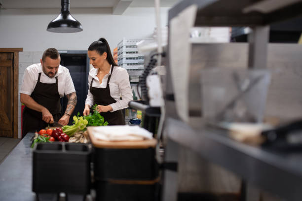 istock Chef teaching how to cook, cutting vegetables indoors in commercial kitchen. 1365331263