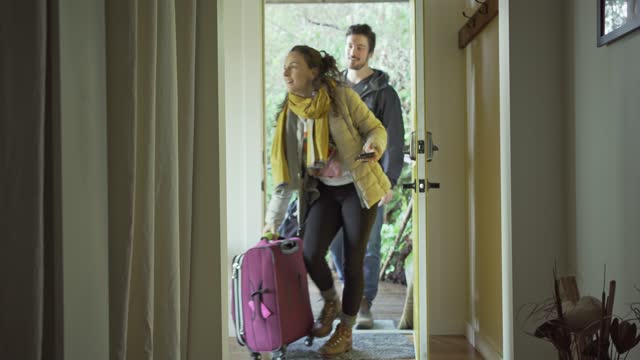 Smiling couple arriving with luggage at their vacation accommodation
