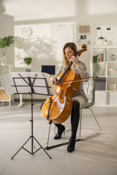 istock Well dressed woman sitting and playing cello in studio 1365331289