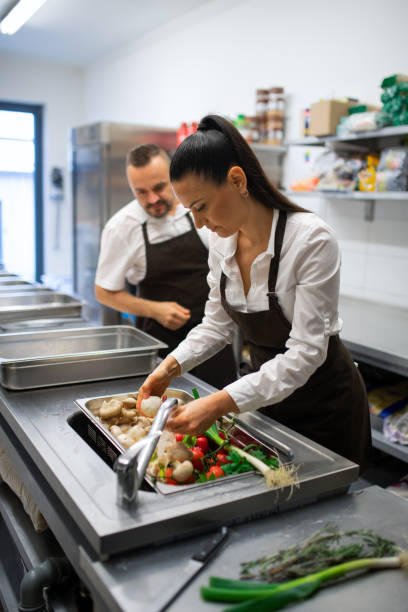 istock Cook washing vegetables in sink in commercial kitchen. 1365331438