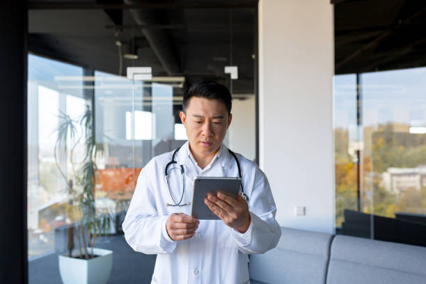 istock Serious Asian doctor, uses a tablet computer, the man works in a modern clinic 1365331859