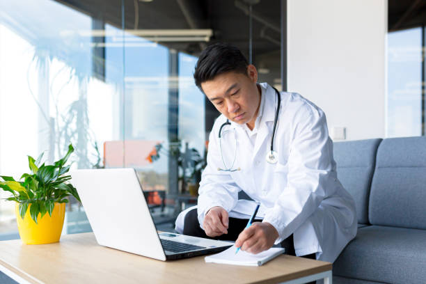 istock Successful Asian doctor working on a laptop in a modern clinic. 1365331873