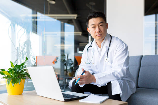 istock Successful Asian doctor working on a laptop in a modern clinic. 1365331876