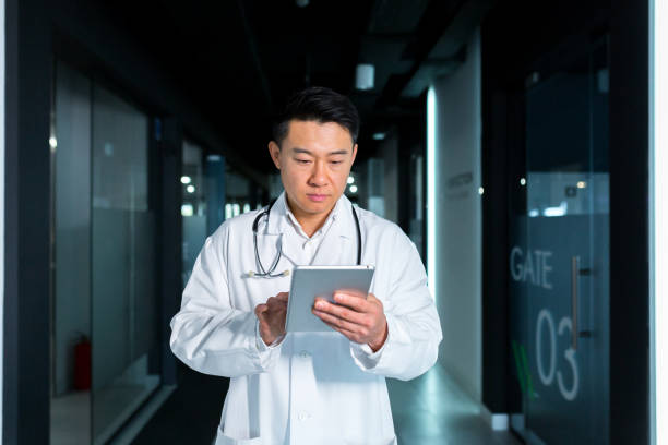 istock Serious Asian doctor, uses a tablet computer, the man works in a modern clinic 1365332010