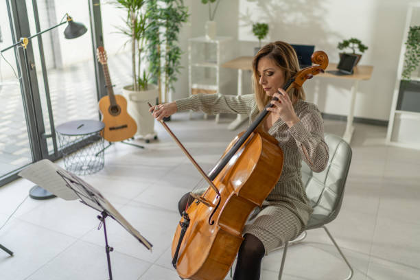 istock Beautiful well dressed woman sitting and playing cello in studio 1365332052
