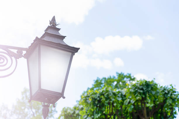 Blurred Summer Day background with Street Black lantern Green trees and Blue Sky