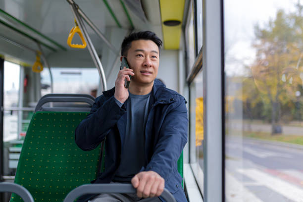 캐주얼 한 옷을 입고 휴대 전화에서 이야기하는 재미가있는 공공 버스 승객의 아시아 남자 - bus commuter passenger mobile phone 뉴스 사진 이미지