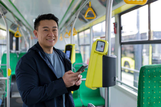 istock Happy and successful asian male passenger in public transport bought a ticket using a mobile phone smiling and looking at the camera 1365333821