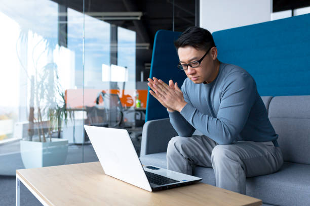 istock Pensive asian man working from office sitting at desk, making important decision, serious and focused businessman 1365334204