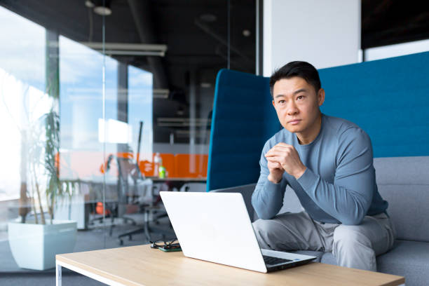 istock A thinking Asian man works at a computer in a modern office, a freelancer is focused on solving a task, makes an important job. 1365334206