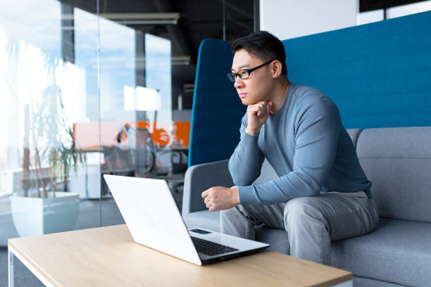 istock Pensive businessman in modern office working on laptop asian boss makes difficult choice 1365334211