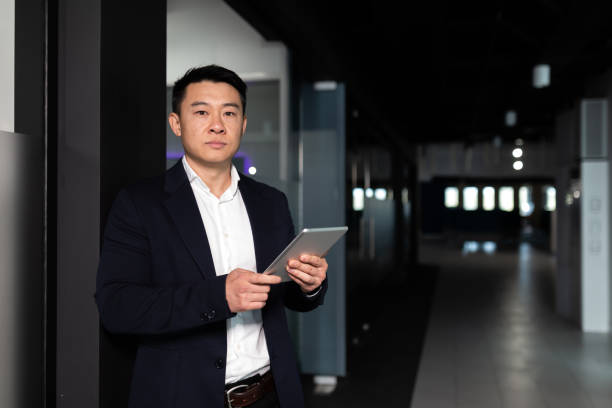 istock Serious asian male worker focused on work working with tablet computer in modern office 1365334296