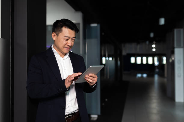 심각한 아시아 남성 노동자는 현대 사무실에서 태블릿 컴퓨터와 함께 작업에 초점을 맞춘 - people office mobility looking 뉴스 사진 이미지