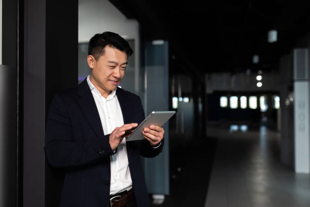 istock Serious asian male worker focused on work working with tablet computer in modern office 1365334303