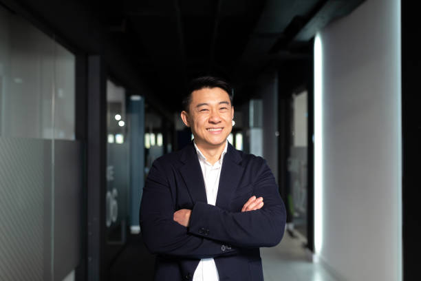 istock Successful startup asian man, businessman looking at camera, smiling and rejoicing in modern office, arms crossed 1365334308