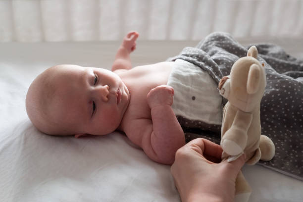 istock Baby boy resting in bed playing with his teddy bear. 1365338075