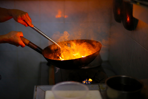 The wok in fire during frying green vegetable at home kitchen.
