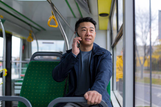 불안하고 무서운 아시아 남자, 공공 버스를 타고, 승객이 휴대 전화에 이야기 - color image bus discussion expertise 뉴스 사진 이미지