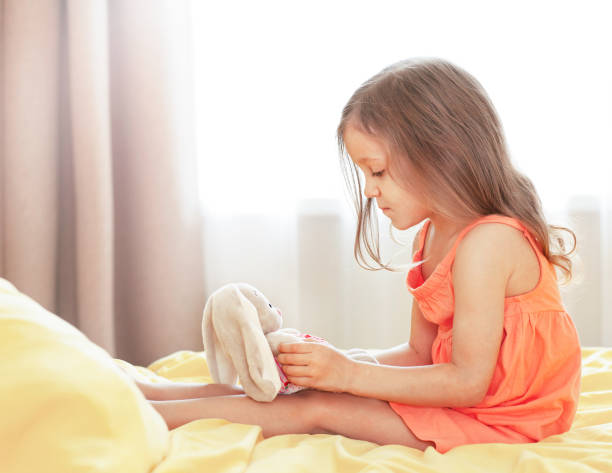 istock little girl on the bed with a plush bunny 1365341356