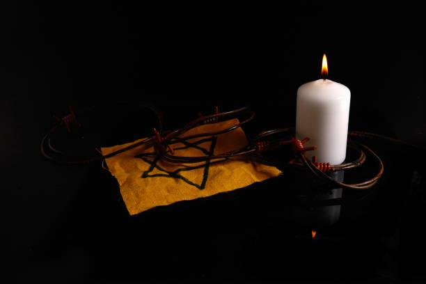 istock Holocaust memory day. Arbed wire and burning candle on black background 1365344765