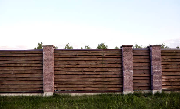 istock Brown wooden fence with block posts. Construction site. Corrugated surface. Private property fencing. Opaque hedge. Countryside backyard security exterior. Scandinavian, chalet or rustic style. DIY 1365345172