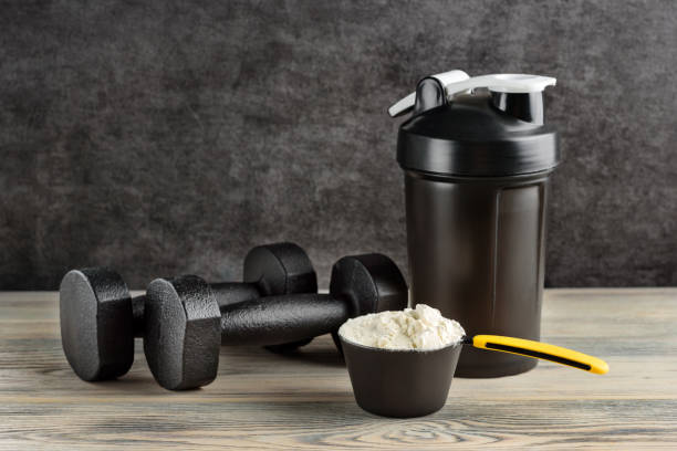 a measuring spoon with protein, a sports shaker and a pair of dumbbells close-up. - body building milk shake protein drink drink imagens e fotografias de stock