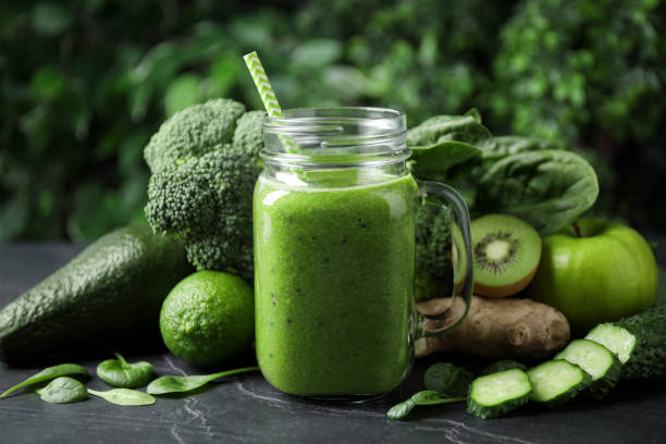 istock Delicious green juice and fresh ingredients on black table 1365349041