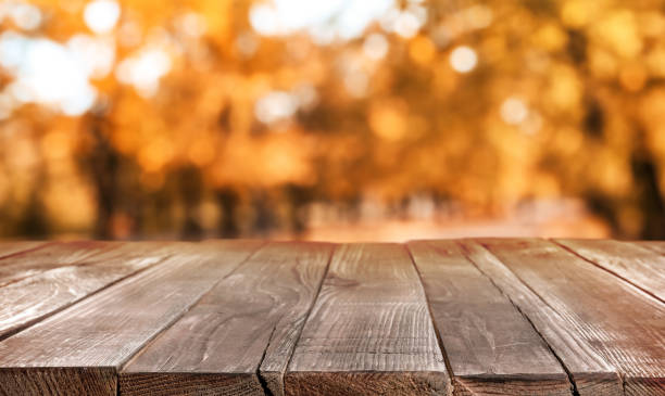 istock Empty wooden table in beautiful autumn park 1365349346