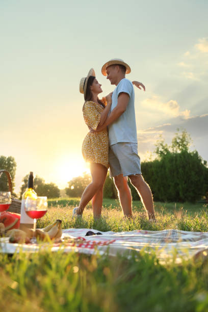 счастливая пара обнимается на пикнике в парке - love anniversary lifestyles outdoors стоковые фото и изображения