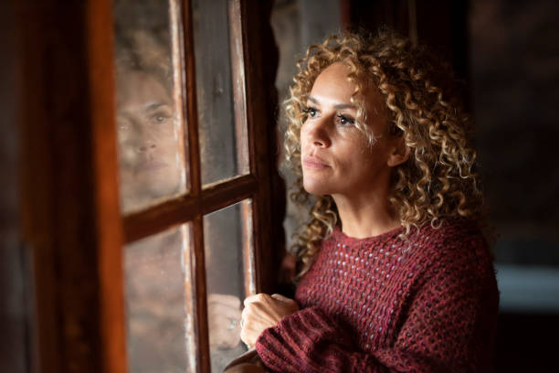 istock Woman Looking Away While Standing By Window 1365352699