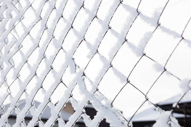 istock Covered with snow mesh net with cloudy sky and few buildings in background closing restricted area. Exile to Siberia. Protests with people going out to rallies 1365356270