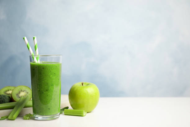 istock Delicious green juice and fresh ingredients on white table against light blue background, space for text 1365356783