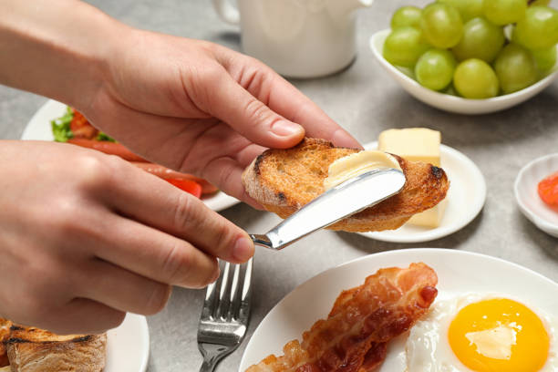 istock Woman spreading butter on toast at table, closeup. Buffet service 1365358523