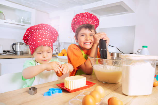 istock Boy mix dough in bowl make cookies with brother 1365363425