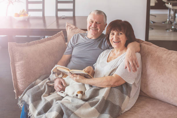 istock Happy elderly couple sitting on sofa at home 1365366150