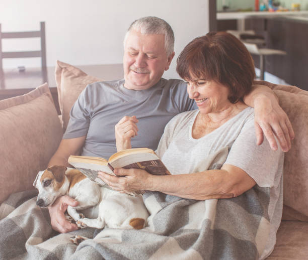 istock Happy elderly couple sitting on sofa at home 1365366341