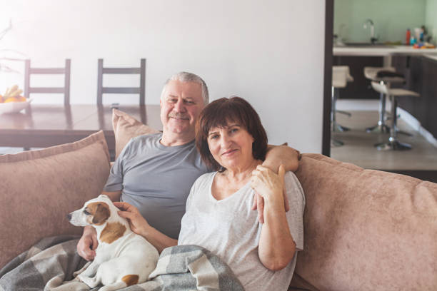 istock Happy elderly couple sitting on sofa at home 1365366364