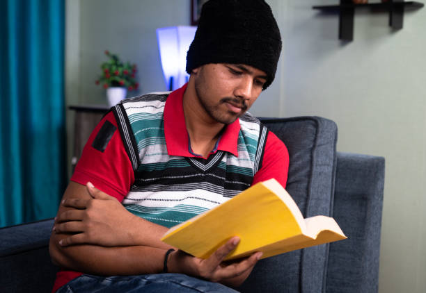 joven leyendo libros usando suéter y gorra durante la helada temporada de invierno en casa: concepto de trabajo duro e inteligente, estudio para el examen, el desarrollo de habilidades y conocimientos - motivation passion cold inspiration fotografías e imágenes de stock