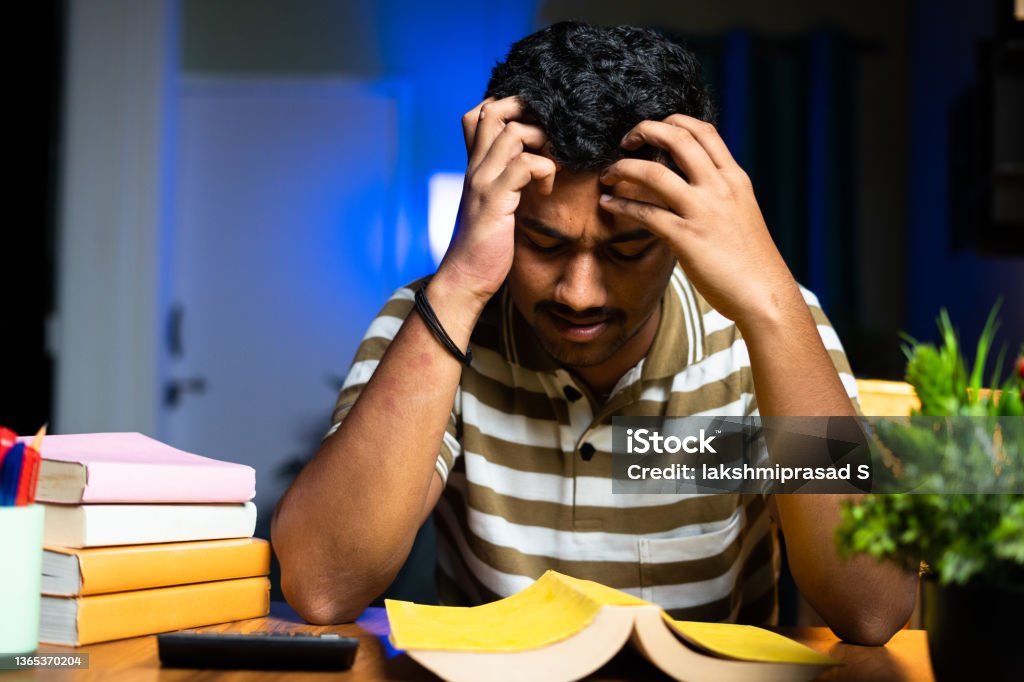 Young student reading on midnight exam preparation reading not understanding books at home - concept of reading problem or difficulties, trouble seeing at night studying Young student reading on midnight exam preparation reading not understanding books at home - concept of reading problem or difficulties, trouble seeing at night studying. India Stock Photo