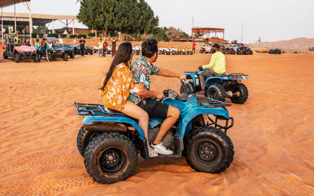 18 novembre 2021 émirats arabes unis, dubaï - heureux quads conduisant dans les dunes de sable. jeune couple actif dans une activité de plein air conduisant un quad vtt dans le désert, dubaï, émirats arabes unis - 4x4 desert sports utility vehicle dubai photos et images de collection