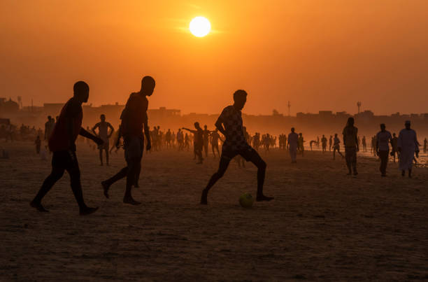 Brazilian people playing soccer football in a golden sunset afternoon at Posto Nove on Ipanema Beach Rio de Janeiro Brazil